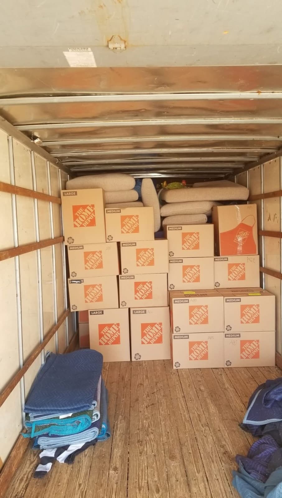 Moving boxes packed and stacked neatly inside a truck, with furniture blankets on the floor