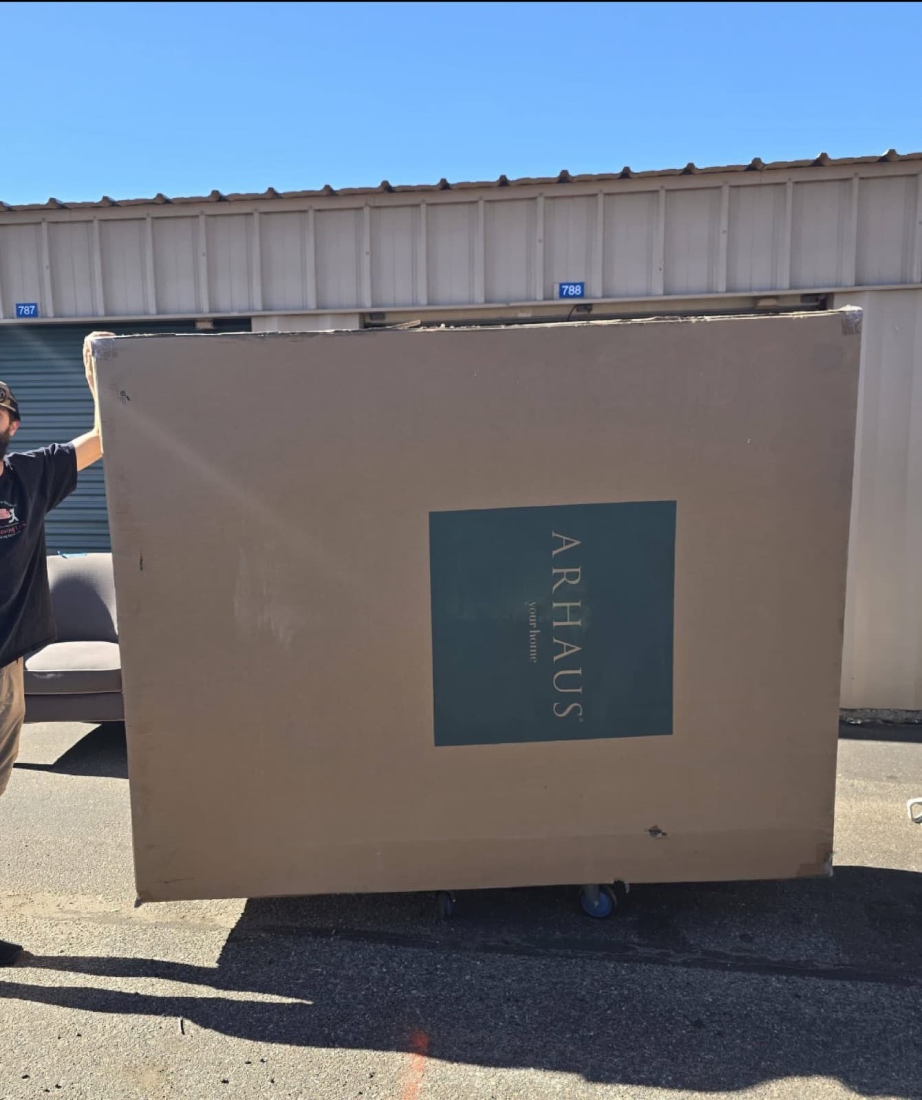 A Heritage Moving crew member handling an oversized Arhaus furniture crate on a dolly
