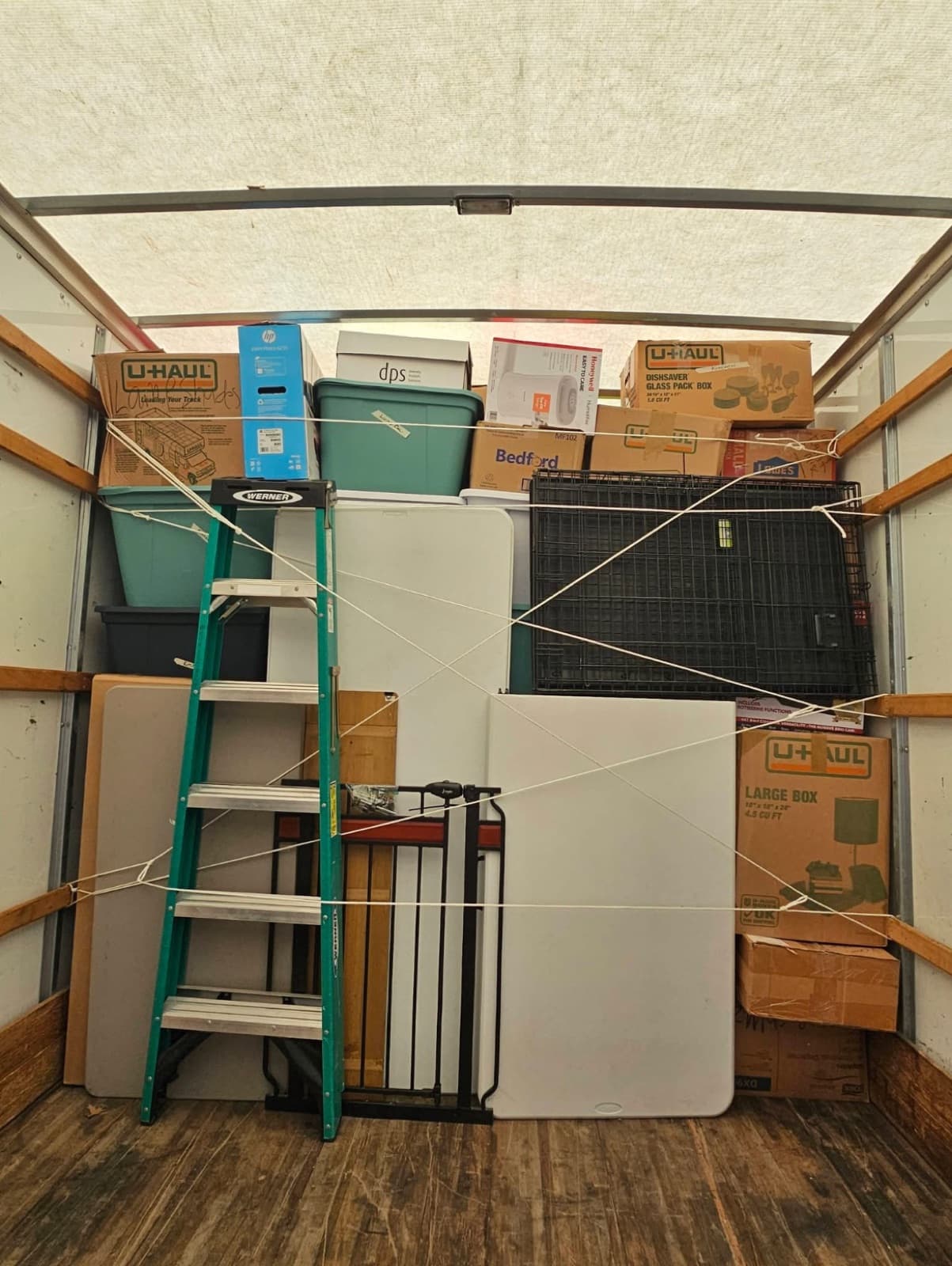 Rental truck loaded tight with a refrigerator, ladder, and boxes — strapped down for the drive