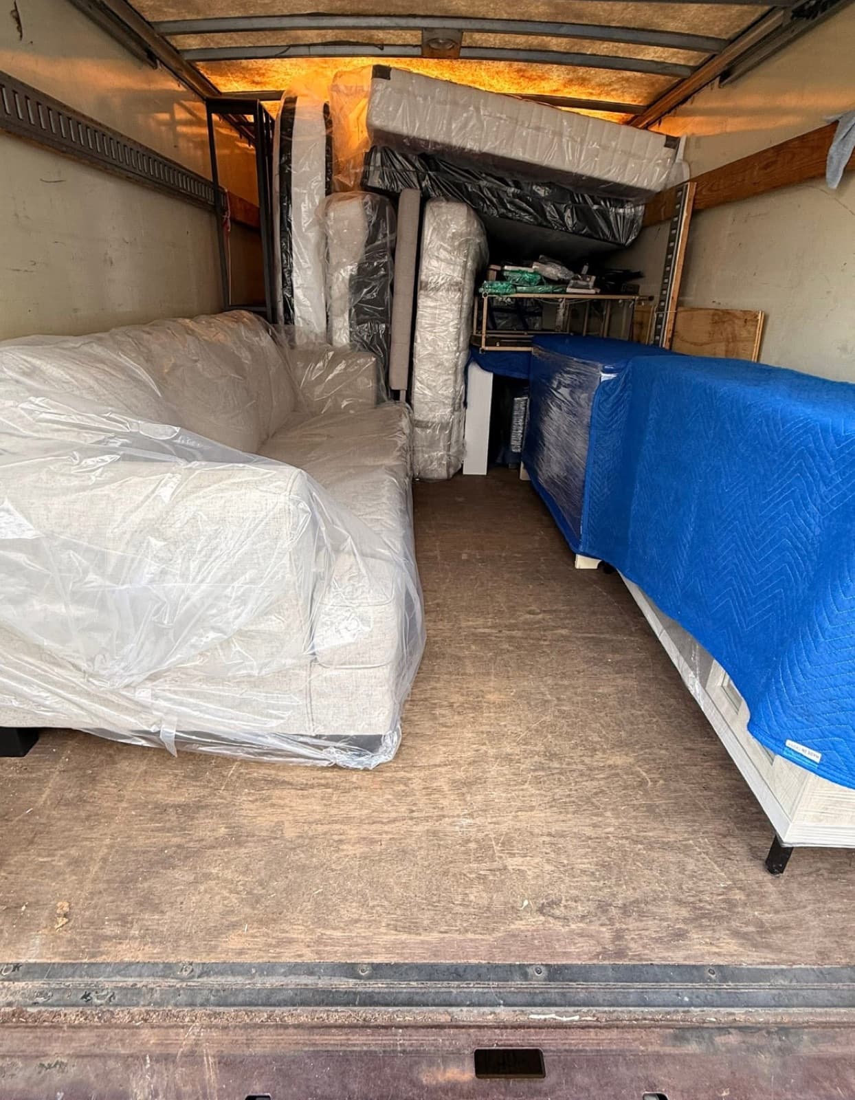 Couch and dresser shrink-wrapped and blanket-padded in the back of a Heritage Moving truck